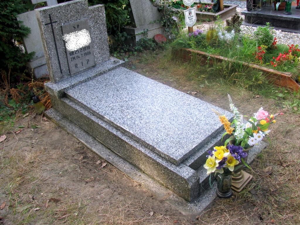 Szary, granitowy nagrobek z krzyżem, po czyszczeniu i impregnacji, z datami urodzin i śmierci, ozdobiony bukietem kolorowych kwiatów w wazonie, umieszczony na cmentarzu.